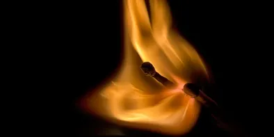 Flacara de la doua faclii văzuta de aproape pe fond negru