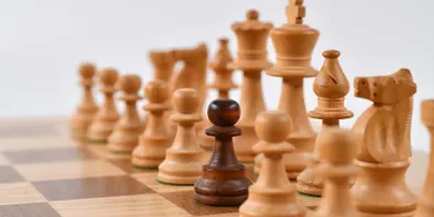 Piesele albe de sah aranjate pe o tabla, dar cu un pion negru, văzute de aproape