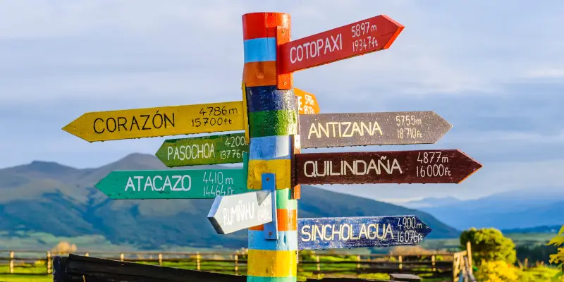 Mai multe indicatoare de orase, cu distante pe ele, colorate, catre diverse directii