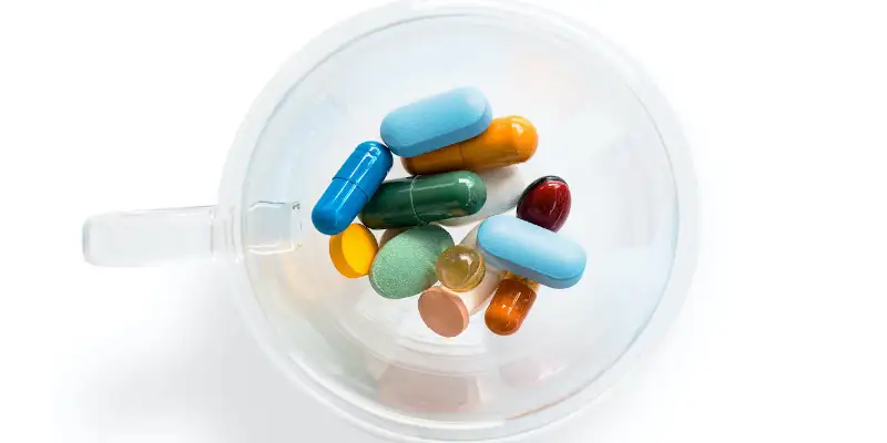 O ceasca transparenta cu pastile frumos colorate, pe un fundal alb