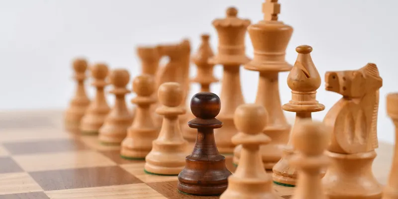 Piesele albe de sah aranjate pe o tabla, dar cu un pion negru, văzute de aproape